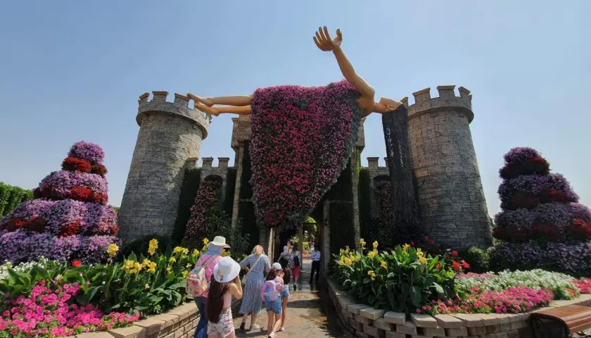 Niesamowity **Miracle Garden w Dubaju** zachwyca kwitnącą rzeźbą człowieka na tle zamku. Kolorowe kwiaty tworzą bajkową scenerię.