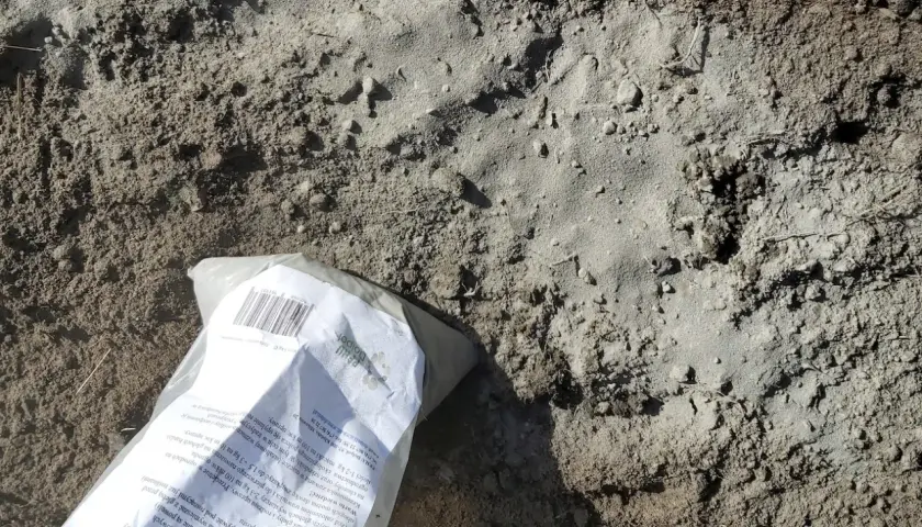 Opakowanie mączki bazaltowej leży na ziemi. Czy mączka bazaltowa jest szkodliwa? To naturalny nawóz, który poprawia strukturę gleby i dostarcza minerałów.