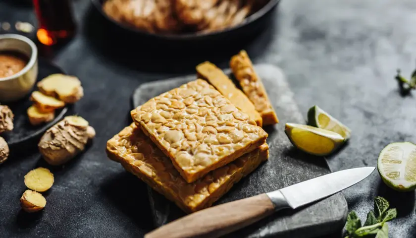 Pezzi di tempeh in agrodolce pronti per essere cucinati, con zenzero, lime e menta.