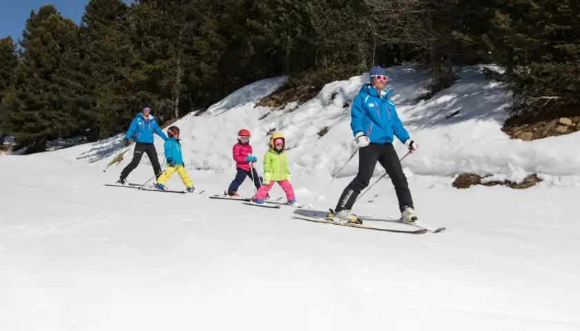 Maestro di sci guida bambini su piste innevate, un'ottima idea per dove sciare con bambini.
