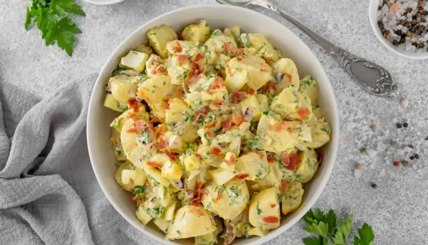 Deliciosa ensalada de patata cremosa con trozos de huevo duro, tocino crujiente y perejil fresco.
