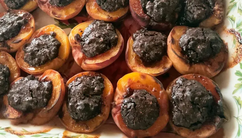 Deliziose pesche ripiene al forno, con un ripieno scuro e invitante, pronte per essere gustate.
