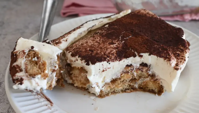 Fetta di tiramisù con abbondante crema al mascarpone 500 g, cosparsa di cacao amaro.