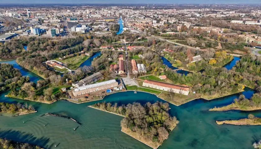 Marghera: cosa vedere? Un'area verde con canali, edifici storici e la città sullo sfondo.