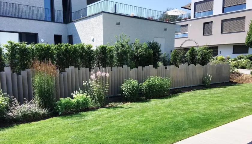 Moderne Zaunelemente bieten tolle **Sichtschutz Garten Ideen**. Ein gepflegter Rasen und üppige Pflanzen ergänzen die Architektur.