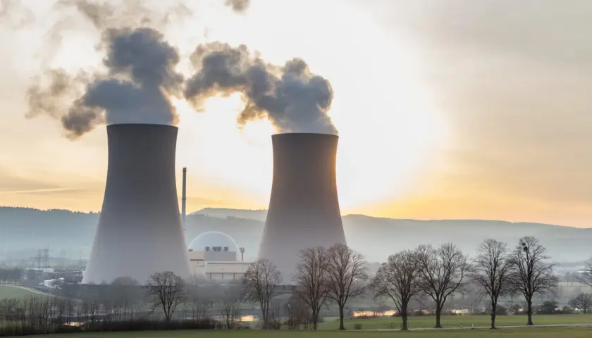 Dwie chłodnie kominowe elektrowni atomowej na tle zachodzącego słońca. Warto wiedzieć, ile prądu produkuje elektrownia atomowa.