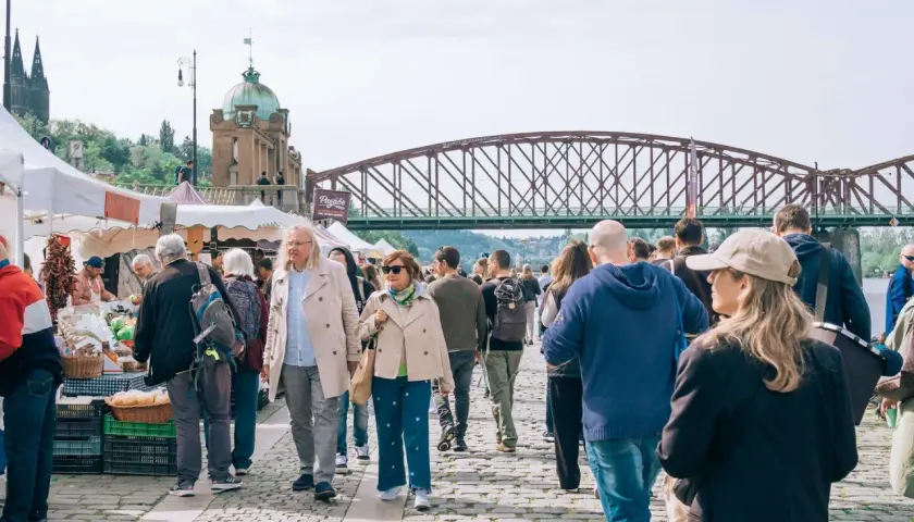 Tłum ludzi na targu, most w tle. Może to być scena z jednego z miast w rankingu miast w Polsce.