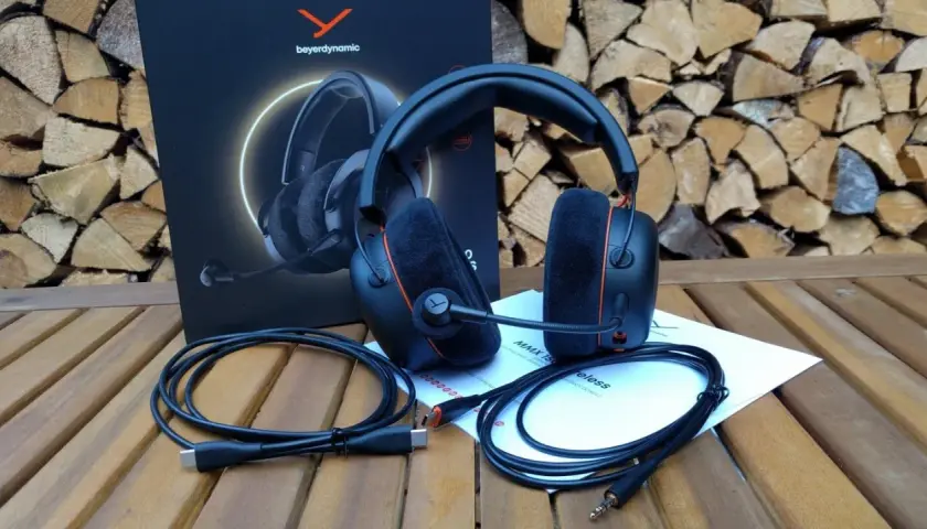 Beyerdynamic MMX 150 Test: Gaming-Headset mit Mikrofon, Kabeln und Anleitung auf Holztisch vor Holzstapel.