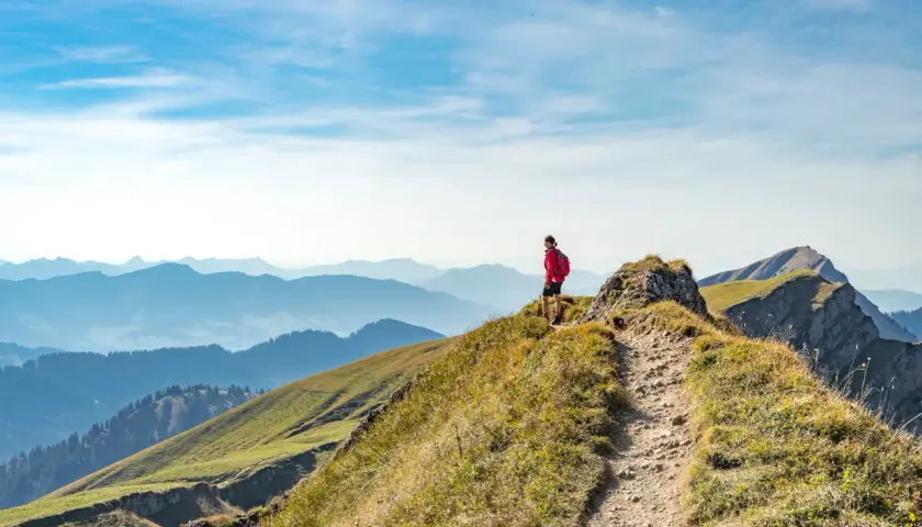 Wanderer auf einem Bergkamm in Deutschland, mit Blick auf eine weite Alpenlandschaft.