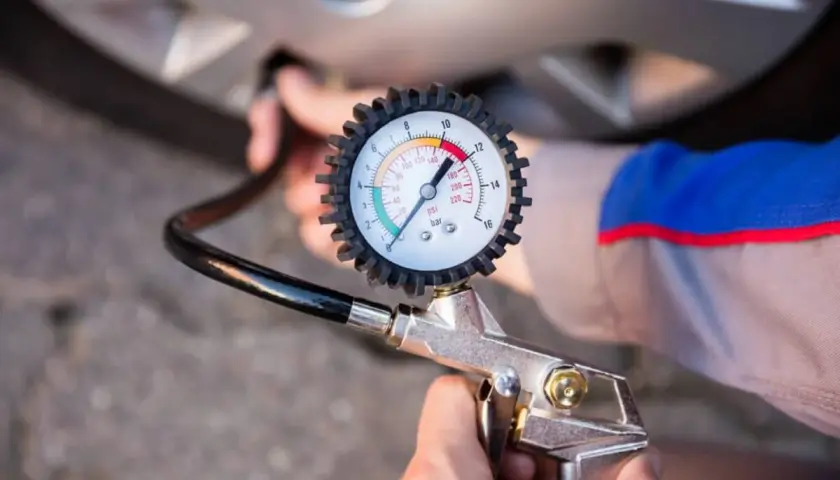 Manómetro de presión de neumáticos conectado a la válvula de una rueda. Aprende como saber la presion de las ruedas del coche para mayor seguridad.