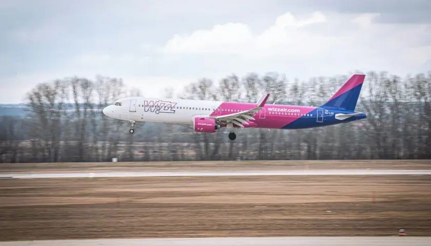 Samolot Wizz Air z wysuniętym podwoziem ląduje na pasie startowym.
