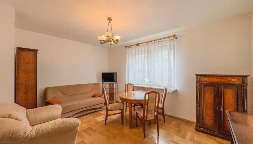 Przytulny salon z kanapą, fotelem i stołem z krzesłami. Klasyczne meble tworzą atmosferę domowego ciepła w tym aurec home.