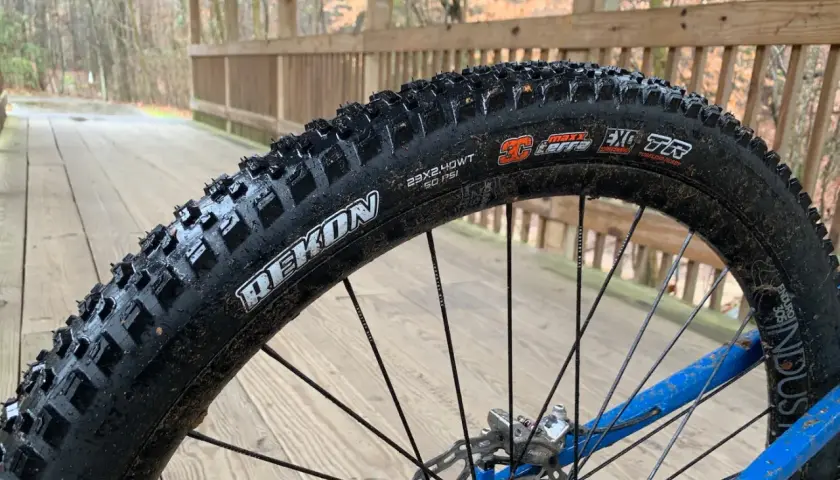 Maxxis Rekon tire on a wet wooden bridge. These tires are great for trail riding, offering excellent grip and durability.