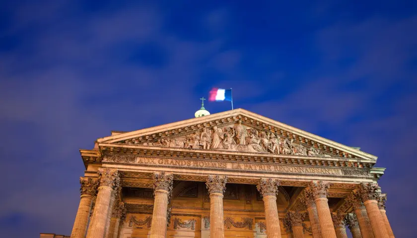 Panteon w Paryżu, symbol tego, z czego słynie Francja: wielkości i sztuki. Flaga Francji powiewa na tle nocnego nieba.