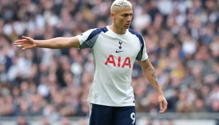 Piłkarz Tottenhamu z blond włosami w białej koszulce z logo AIA na tle trybun.