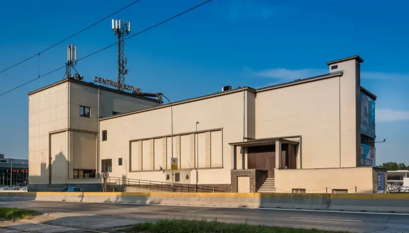 Betonowy budynek z napisem "CENTRUM SZTUKI" na dachu, z wieżami telekomunikacyjnymi. Obok widoczna droga i zieleń.