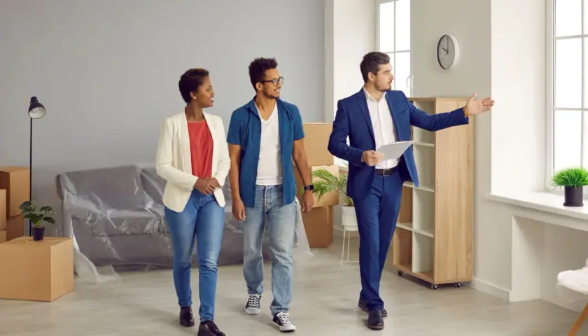 Un agent immobilier présente un appartement à un couple. Ils consultent leur checklist visite appartement.