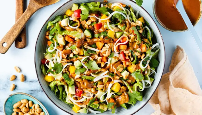 Bunter Sommerrollen Salat mit Reisnudeln, Mango, Avocado, Erdnüssen und cremiger Erdnusssauce.
