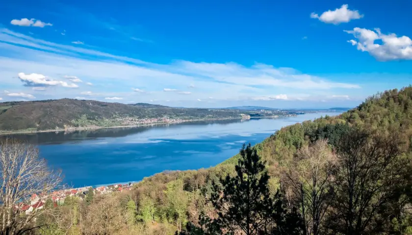 Blick auf einen breiten Fluss mit einer Stadt am Ufer, umgeben von bewaldeten Hügeln. Ein echter **Geheimtipp Urlaub Deutschland**!
