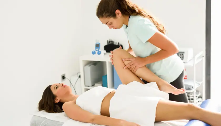 Fizjoterapeuta wykonuje ćwiczenia z pacjentką. Czy fizjoterapeuta to lekarz? Nie, to specjalista rehabilitacji.