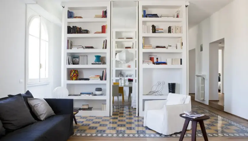 Parete divisoria in cartongesso con librerie bianche e nicchie decorative.
