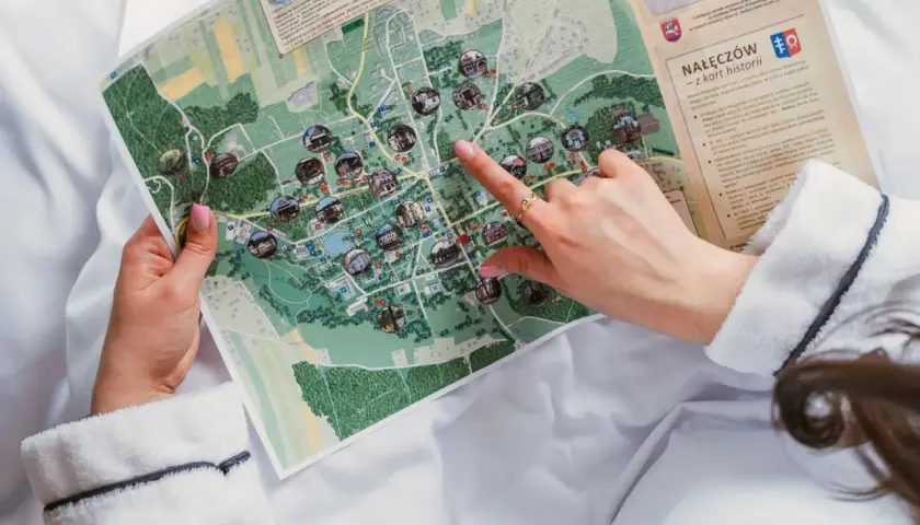 Ręka wskazuje na mapę Nałęczowa, planując, kiedy są wakacje i co zwiedzić.