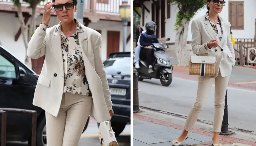 Elegancka kobieta w jasnym garniturze i bluzce w kwiaty. Stylowa torebka. Wskazówka: czego nie nosić po 60.