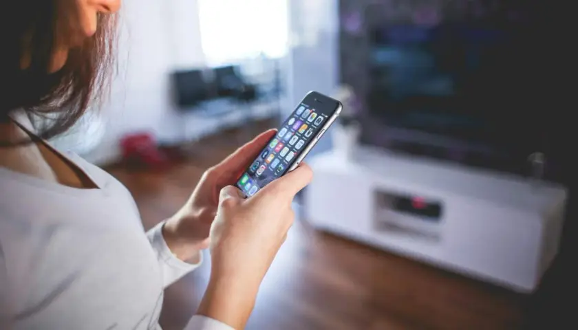 Kobieta steruje inteligentnym domem przez aplikację na smartfonie. Czy to smart life, czy Tuya?