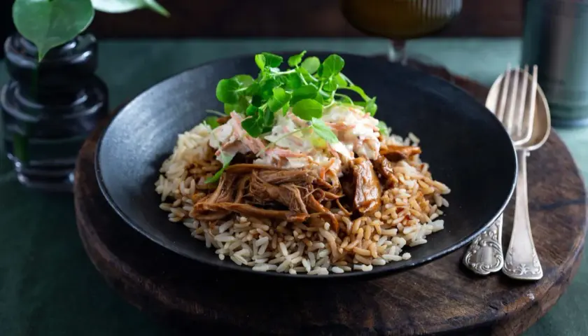 En tallrik med pulled pork med ris, toppad med en krispig coleslaw och färska örter. En härlig måltid!