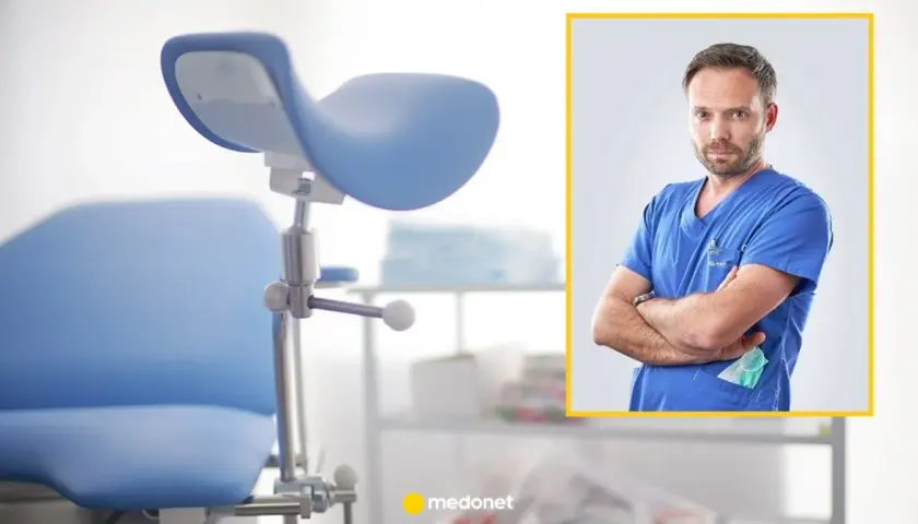 Ginekolog w niebieskim kitlu, z maską w kieszeni, obok fotela ginekologicznego. To miejsce, gdzie kobiety dbają o swoje zdrowie w każdym okresie życia.