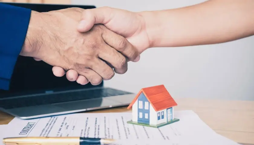 Poignée de main sur un contrat immobilier, symbolisant un accord respectant la loi du 6 juillet 1989 sur les réparations locatives.