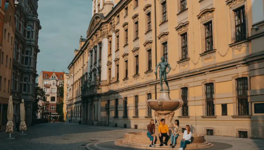 Studenci na wrocławskim Rynku, marzący o doktoracie. Słoneczny dzień, zabytkowa architektura.