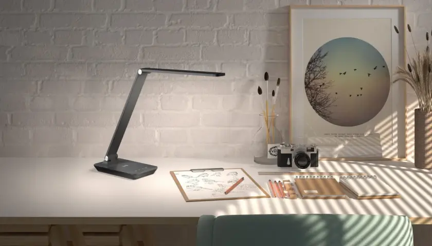 Flexo LED USB moderno sobre escritorio con cámara antigua, bocetos y arte.