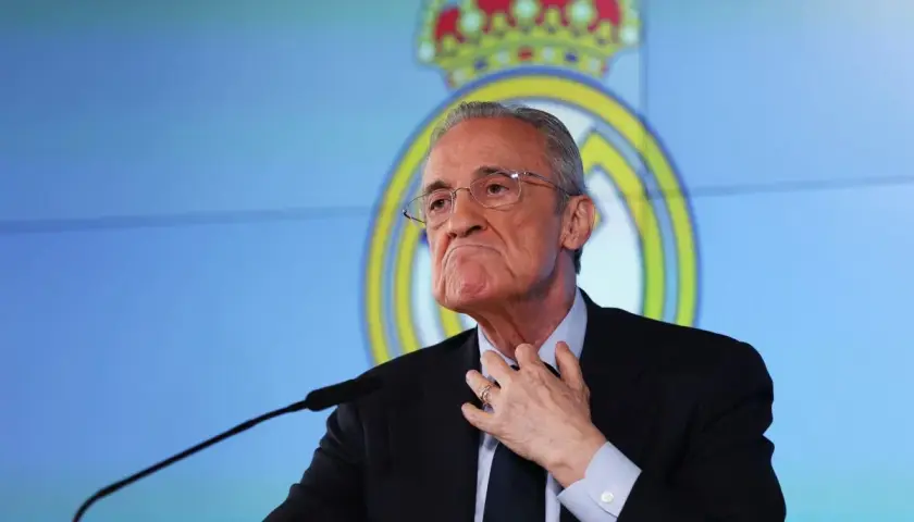 Florentino Pérez, prezes Realu Madryt, w garniturze i okularach, przemawia na tle klubowego logo.
