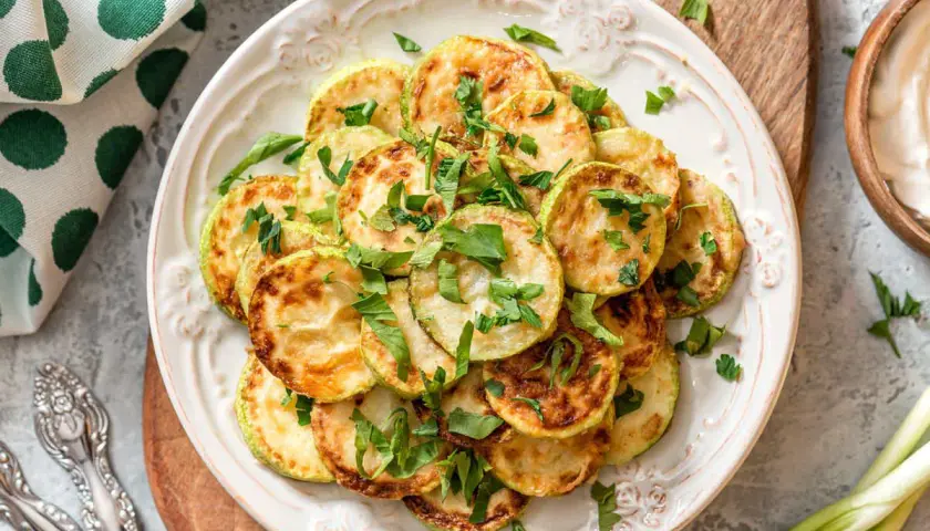 Fette di zucchine dorate e profumate, un'idea per una ricetta zucchine light veloci e gustosa, guarnite con prezzemolo fresco.