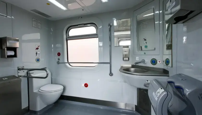 Wnętrze toalety w pociągu Pendolino: biała muszla klozetowa, umywalka, lustro, suszarka do rąk i okno.
