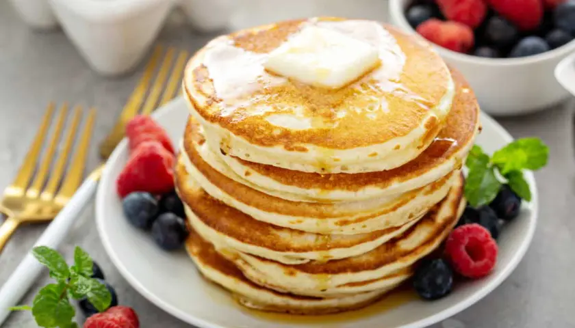 Pile de pancakes sans oeuf, dorés et moelleux, garnis de beurre fondant et de fruits rouges frais. Un délice pour le petit-déjeuner !