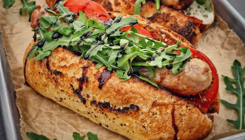 Ein knuspriges Baguette mit einer herzhaften salsiccia italiana, frischen Tomaten und Rucola, beträufelt mit Balsamico.