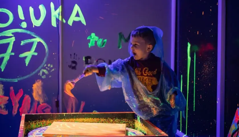 Chłopiec maluje farbami fluorescencyjnymi w ciemni. Niezapomniane urodziny dziecka w Szczecinie.