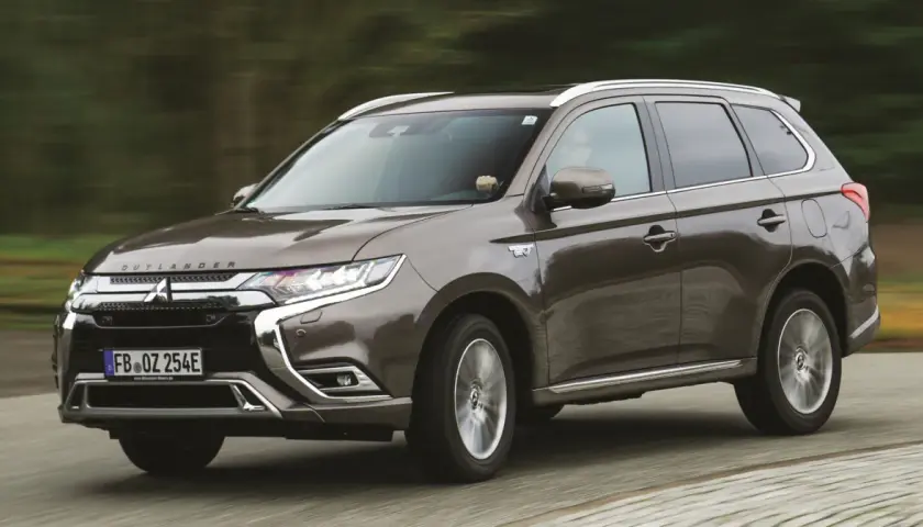 Brązowy Mitsubishi Outlander PHEV jedzie po drodze, zamazane tło sugeruje ruch.
