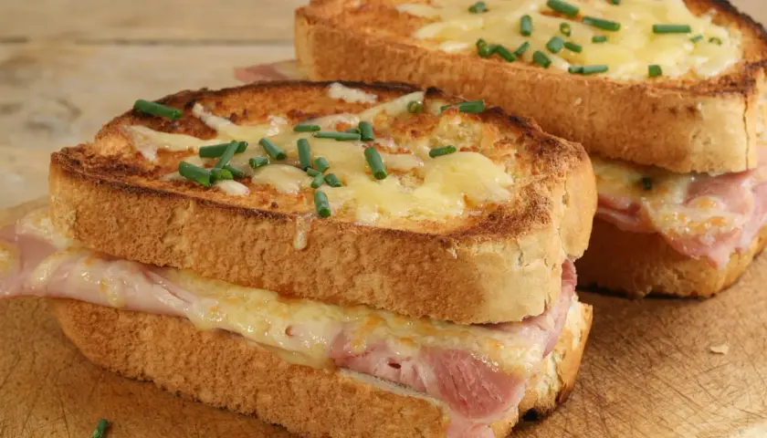 Deux croque monsieur bistrot, dorés et gratinés, garnis de jambon et fromage fondant, parsemés de ciboulette fraîche.