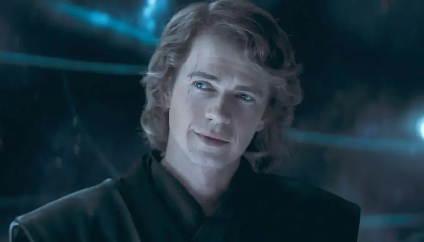Hayden Christensen som Anakin Skywalker, med ett ärr över ögat och ett snett leende, blickar ut i mörkret.