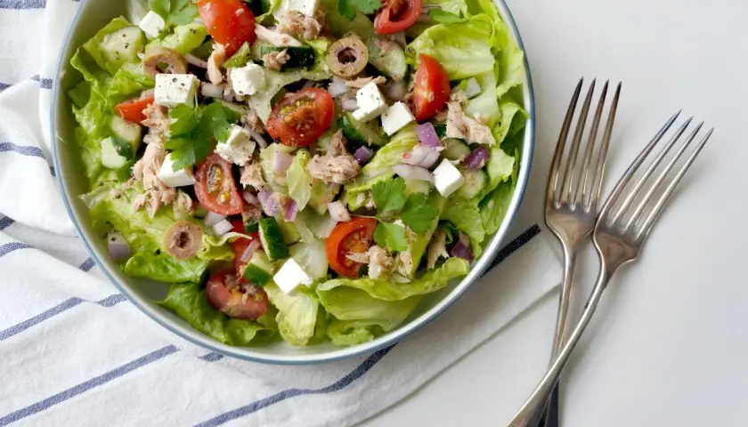 Insalata fresca con lattuga, pomodorini, cetrioli, olive, cipolla rossa, cubetti di feta e tonno sminuzzato.