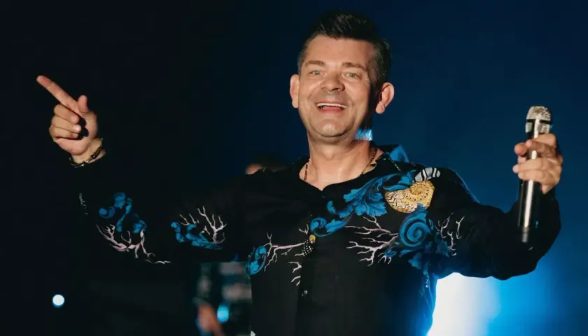 Zenek Martyniuk na scenie, trzyma mikrofon i wskazuje palcem. Szukasz informacji, gdzie najbliższy koncert Zenka Martyniuka?