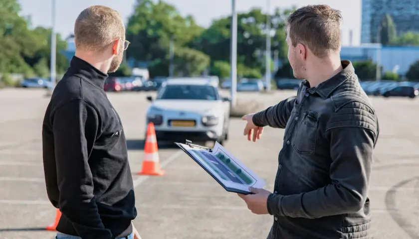 Egzaminator wskazuje na plan placu manewrowego, omawiając jak wygląda egzamin praktyczny kat B.