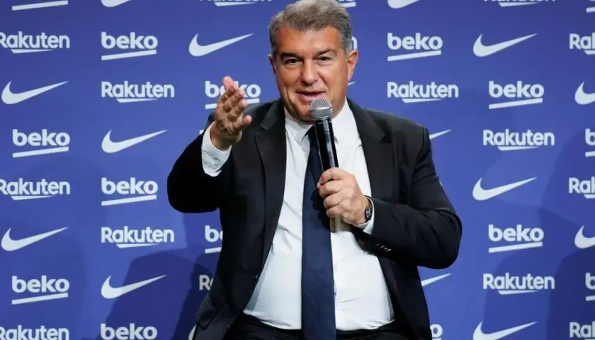 Joan Laporta, prezydent FC Barcelona, przemawia na tle logo klubu. Jego słowa kształtują przyszłość drużyny i jej trenerów.