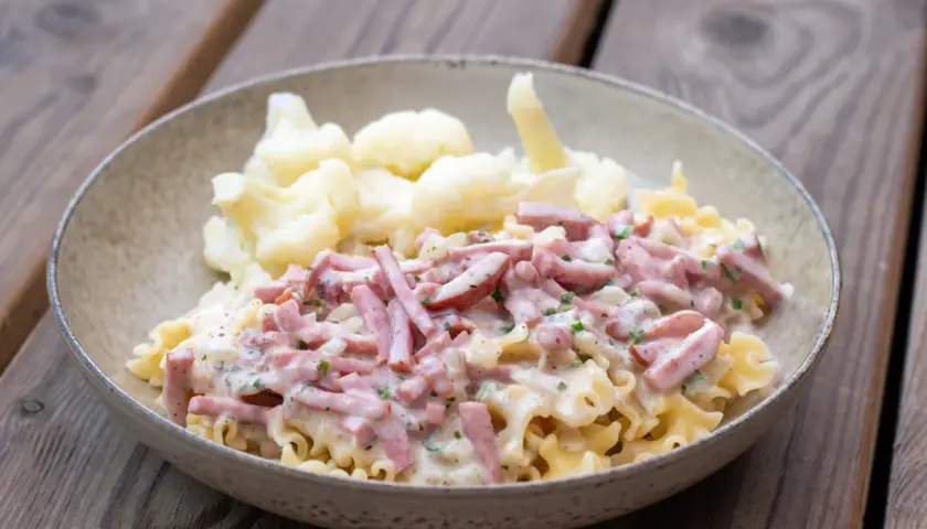 En skål med krusig pasta och skinksås, serverad med blomkål. Enkel och god vardagsmat.