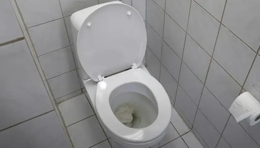 En vit toalett med öppet lock och papper i skålen, vilket indikerar ett stopp i toaletten.