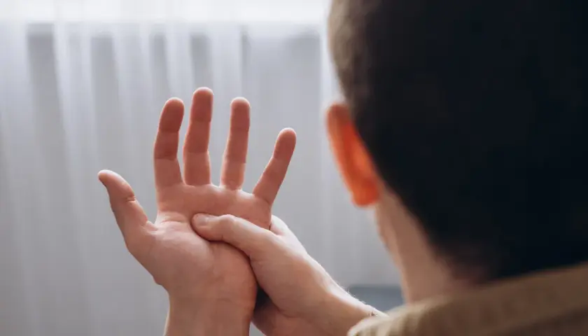 Mężczyzna masuje dłoń, odczuwając drętwienie rąk.