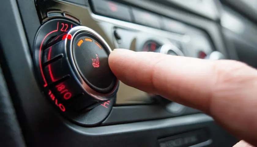 Dedo ajustando el control de temperatura del asiento, mostrando cómo funciona la calefacción de un coche.